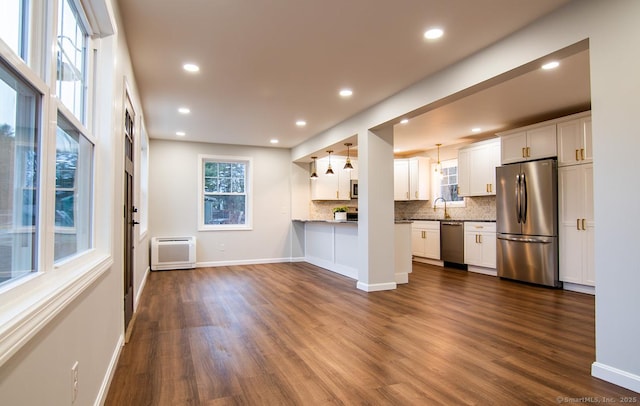 kitchen featuring dark hardwood / wood-style floors, appliances with stainless steel finishes, pendant lighting, and white cabinets