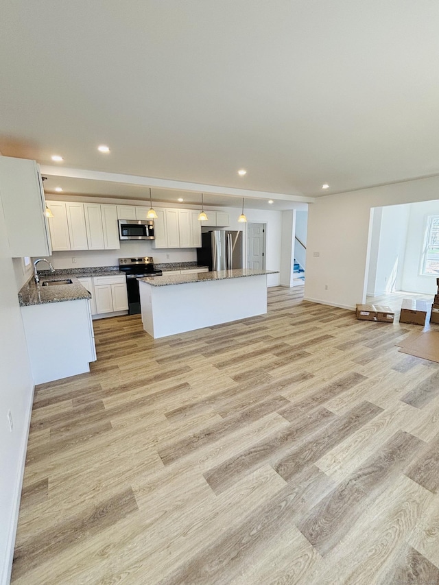 16 Red Bridge Rd, Thompson, CT 06255 - kitchen featuring appliances with stainless steel finishes, a sink, light wood-style floors, white cabinetry, and a center island
