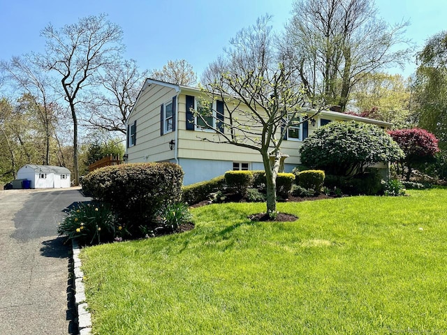 view of side of home with a storage shed and a yard