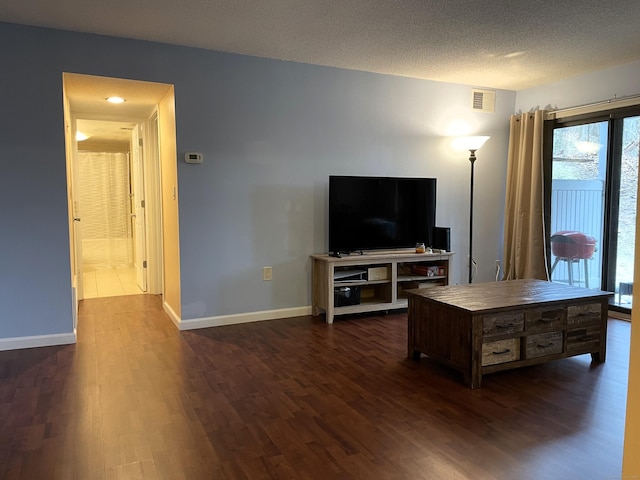 living room with a textured ceiling and dark wood-type flooring