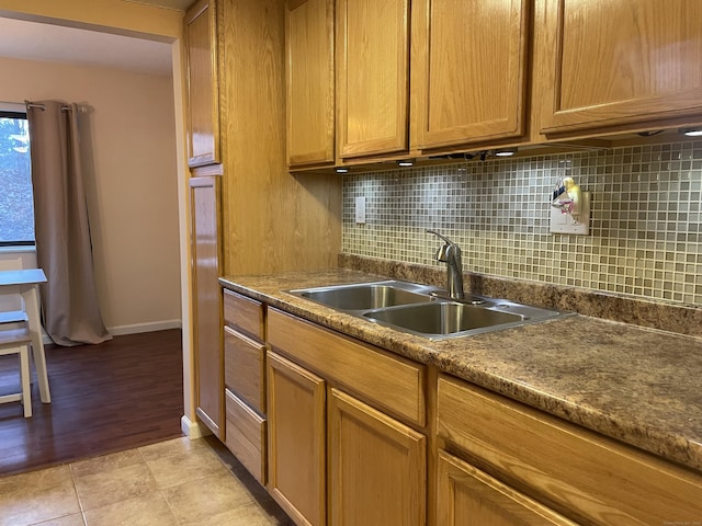 kitchen featuring dark stone countertops, light tile patterned floors, sink, and tasteful backsplash