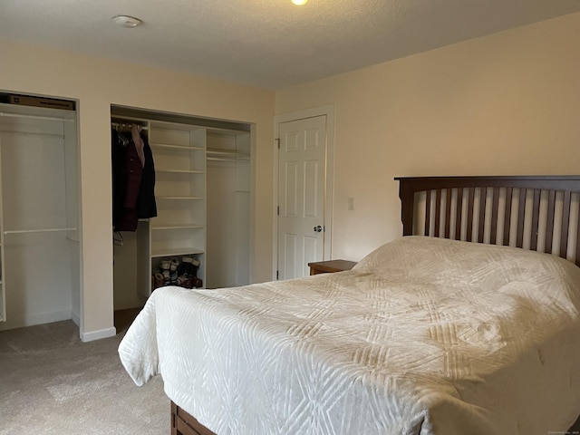 bedroom with multiple closets, carpet floors, and a textured ceiling