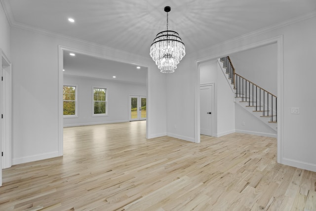 unfurnished living room featuring crown molding, light hardwood / wood-style flooring, and an inviting chandelier