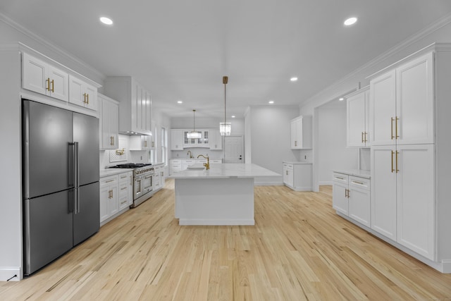 kitchen featuring white cabinetry, hanging light fixtures, premium appliances, backsplash, and an island with sink