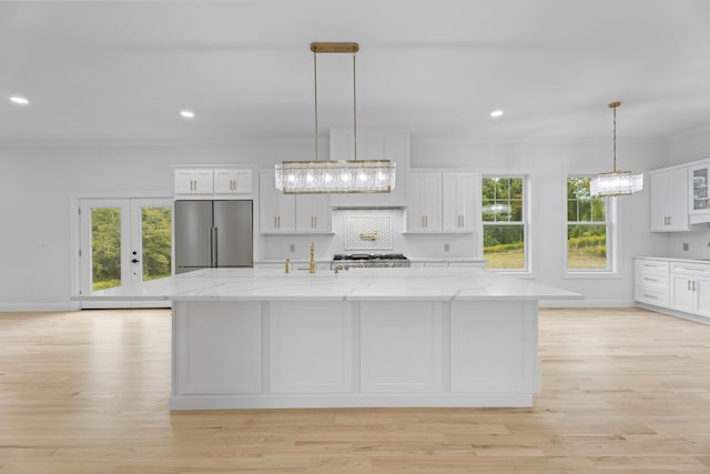 kitchen with white cabinets, high end refrigerator, light stone countertops, and a large island