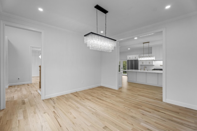 unfurnished dining area featuring light hardwood / wood-style floors, ornamental molding, and a notable chandelier