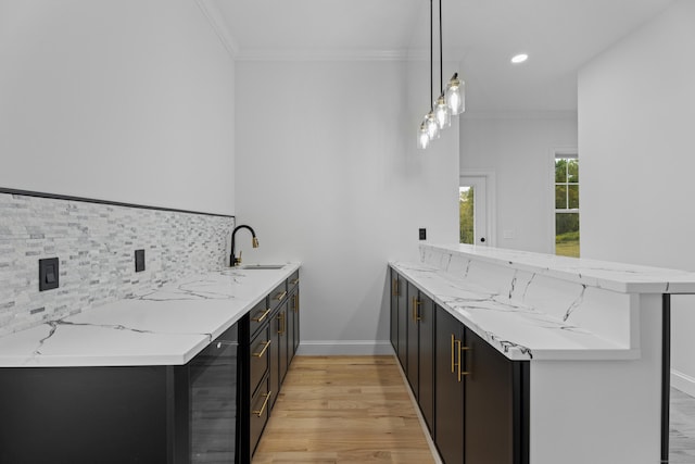 kitchen with sink, light stone counters, kitchen peninsula, and hanging light fixtures