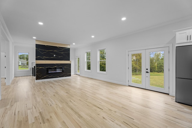 unfurnished living room with french doors, light wood-type flooring, and ornamental molding