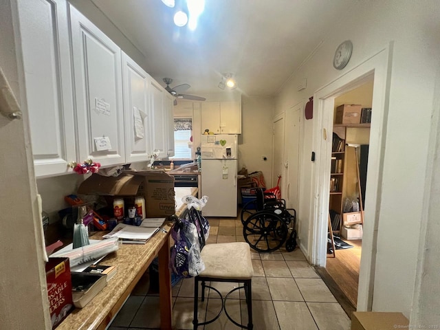 kitchen featuring light tile patterned floors, white fridge, and white cabinetry