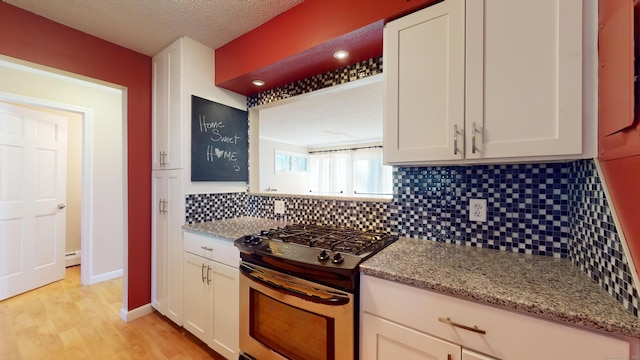 kitchen with light stone countertops, tasteful backsplash, white cabinetry, and stainless steel gas range oven