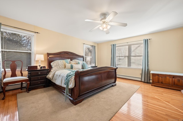 bedroom with multiple windows, ceiling fan, light hardwood / wood-style flooring, and a baseboard radiator