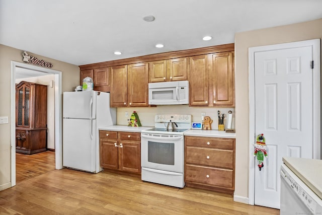 kitchen with white appliances and light hardwood / wood-style flooring