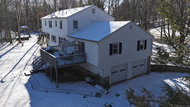 snow covered house with a garage and a wooden deck