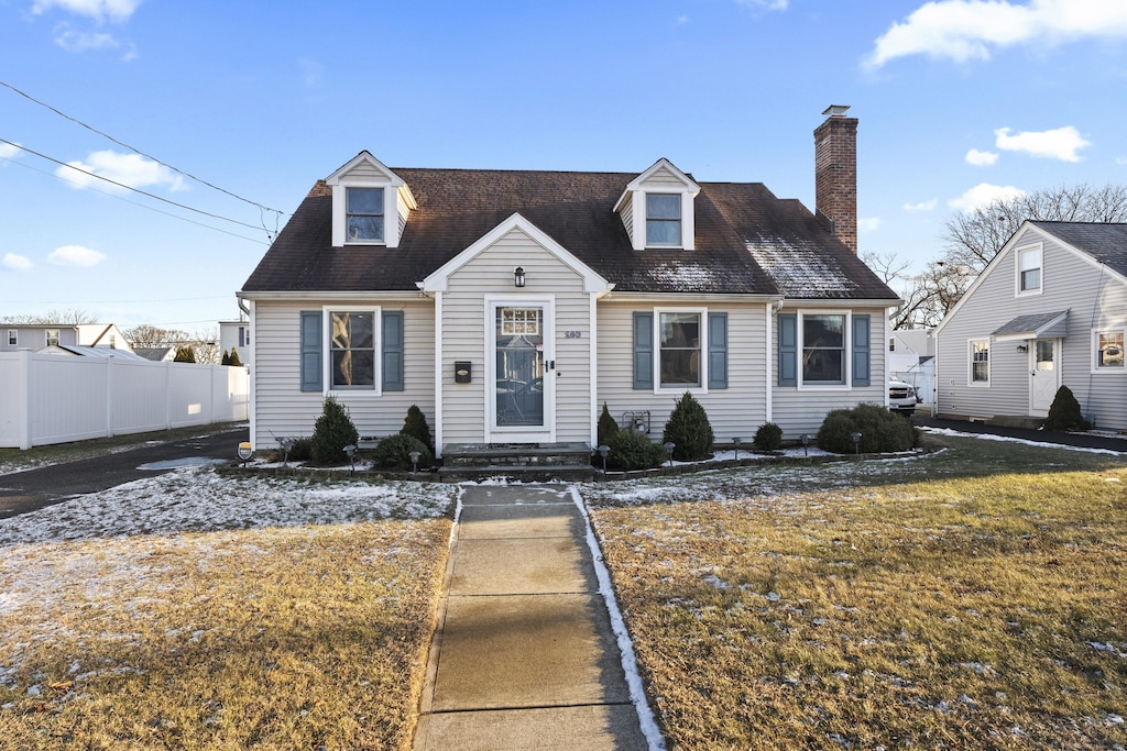 cape cod home featuring a front yard