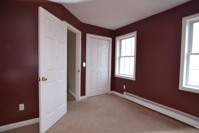 empty room featuring light colored carpet and a baseboard radiator