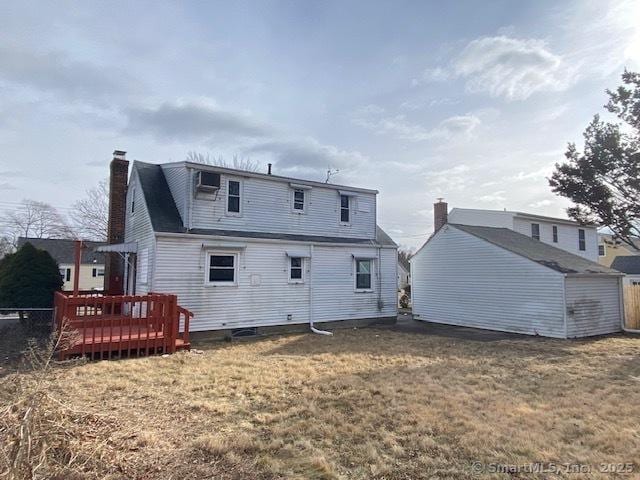 back of house featuring a shed, a wooden deck, and a lawn