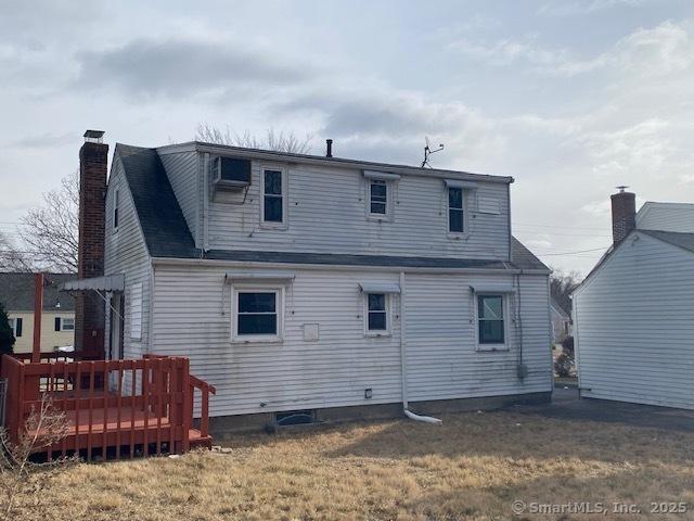 rear view of house featuring a wooden deck and a yard