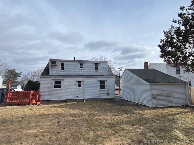 back of house with a lawn, an outdoor structure, and a deck