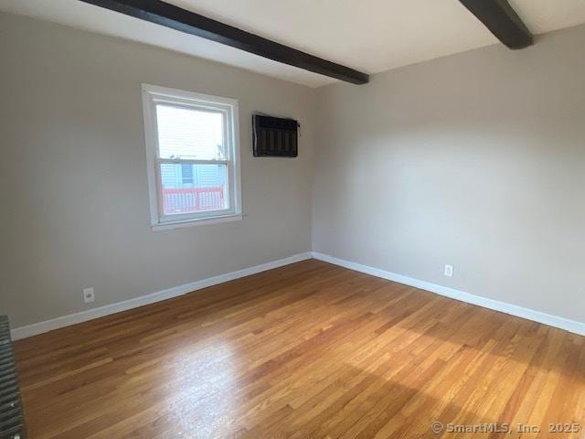 unfurnished room featuring beamed ceiling and wood-type flooring