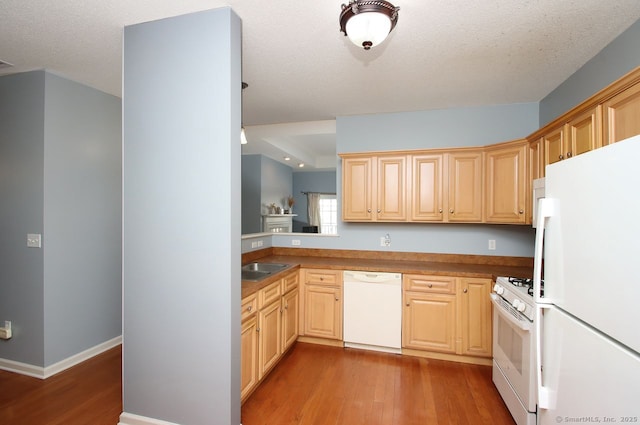 kitchen with light brown cabinetry, white appliances, a textured ceiling, and hardwood / wood-style floors