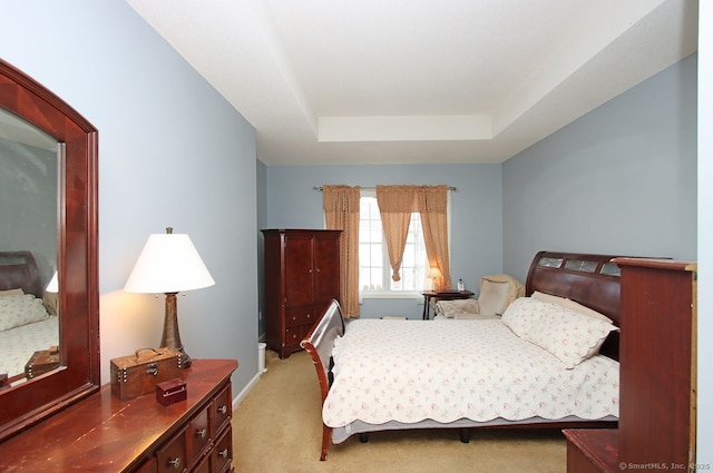 carpeted bedroom featuring a raised ceiling