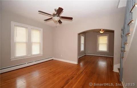 spare room with ceiling fan, dark hardwood / wood-style flooring, and a baseboard heating unit