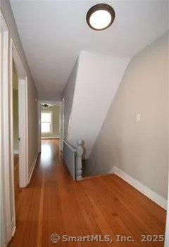 hallway with hardwood / wood-style floors and vaulted ceiling