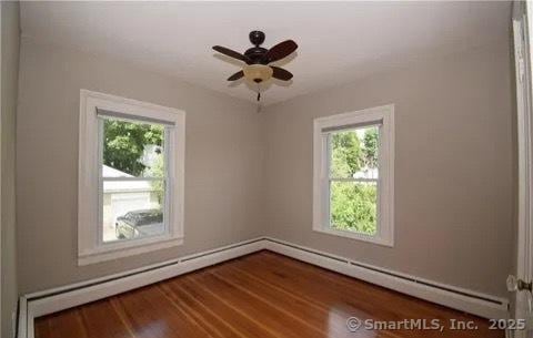 spare room with a baseboard radiator, hardwood / wood-style flooring, and ceiling fan