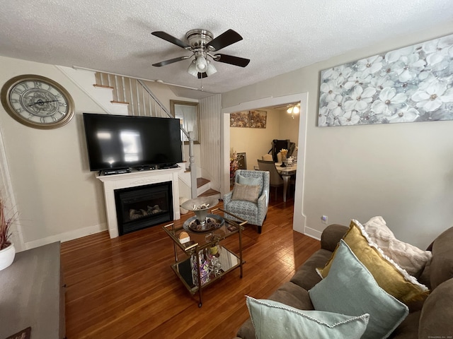 living room featuring ceiling fan, dark hardwood / wood-style flooring, and a textured ceiling