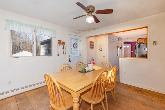 dining area with ceiling fan, light wood-type flooring, and a baseboard heating unit