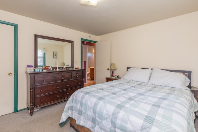 bedroom featuring ensuite bathroom and light carpet