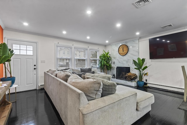 living room featuring dark hardwood / wood-style floors, a healthy amount of sunlight, a high end fireplace, and a baseboard heating unit