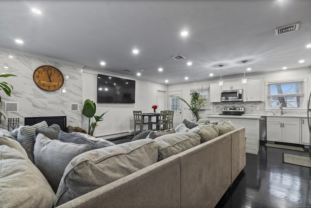 living room featuring crown molding, sink, a fireplace, a baseboard radiator, and dark hardwood / wood-style flooring