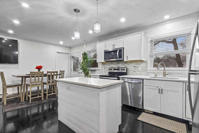 kitchen featuring white cabinets, sink, hanging light fixtures, a kitchen island, and stainless steel appliances