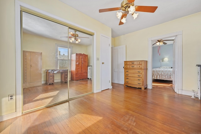 unfurnished bedroom with wood-type flooring, a closet, and ceiling fan