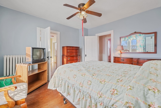 bedroom featuring hardwood / wood-style floors, radiator, and ceiling fan