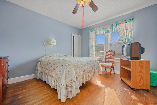 bedroom featuring hardwood / wood-style floors, a textured ceiling, and ceiling fan