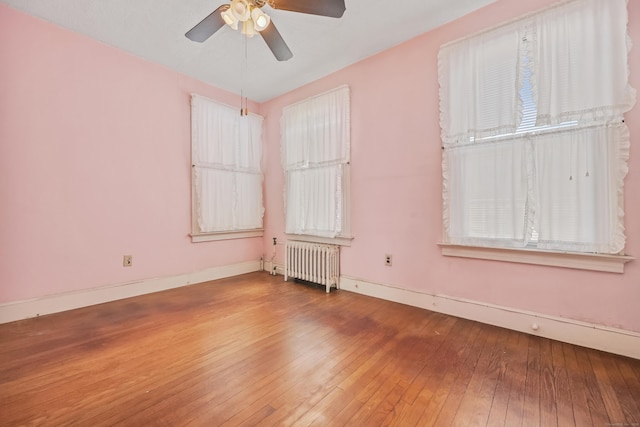 empty room with radiator heating unit, hardwood / wood-style floors, and ceiling fan