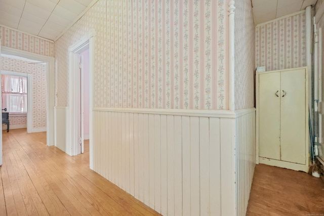 hallway with light hardwood / wood-style flooring and crown molding