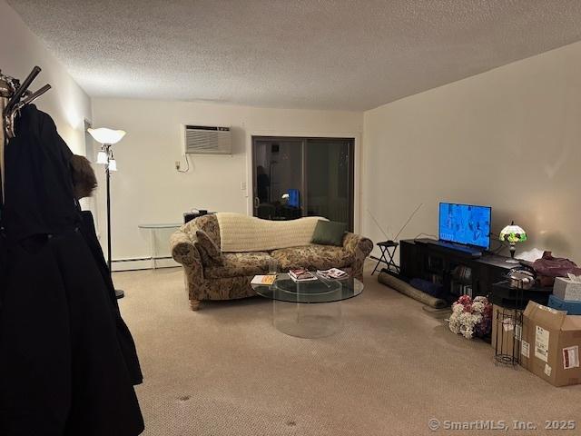 living room with baseboard heating, carpet flooring, a wall mounted air conditioner, and a textured ceiling