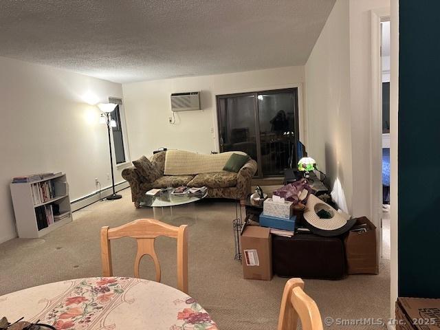 carpeted living room featuring a textured ceiling, a wall unit AC, and a baseboard heating unit