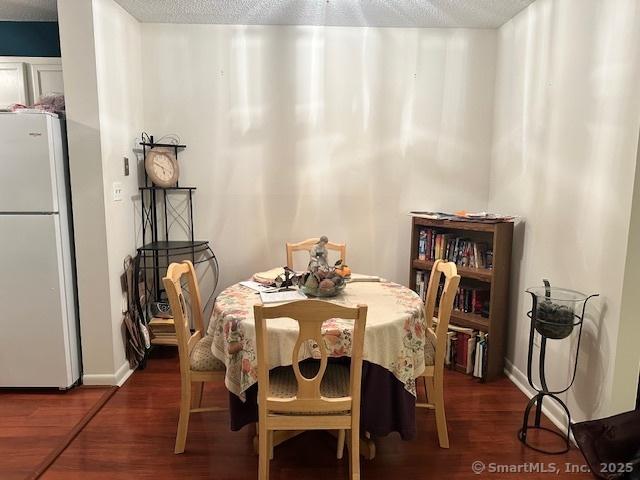 dining room with dark wood-type flooring and a textured ceiling