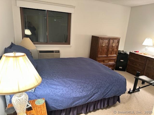 carpeted bedroom featuring a wall unit AC