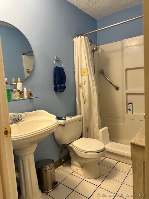 bathroom featuring sink, walk in shower, tile patterned flooring, a textured ceiling, and toilet