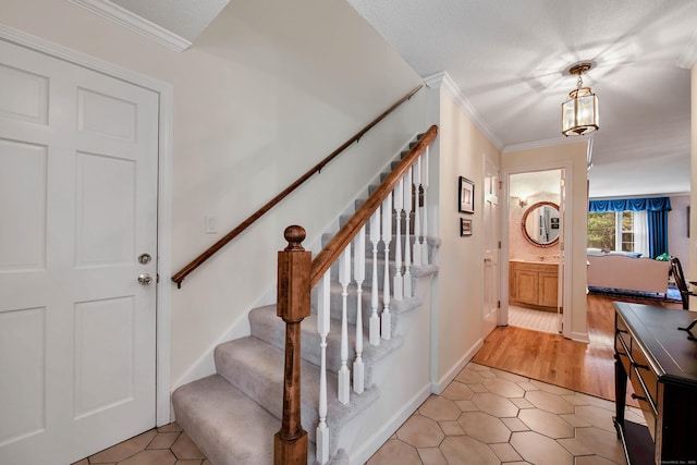 staircase featuring a textured ceiling, ornamental molding, tile patterned floors, and a notable chandelier