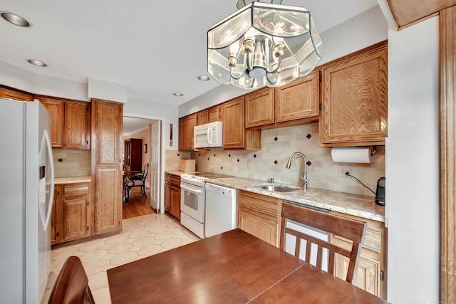 kitchen featuring white appliances, a sink, light countertops, backsplash, and a chandelier