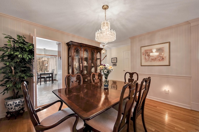 dining space featuring baseboards, a chandelier, crown molding, and light wood finished floors