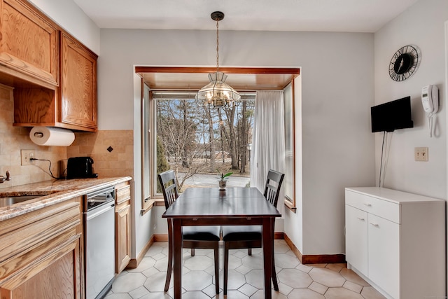 kitchen with backsplash, baseboards, light stone countertops, hanging light fixtures, and a notable chandelier