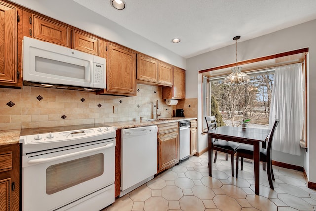 kitchen featuring backsplash, a notable chandelier, brown cabinets, and white appliances