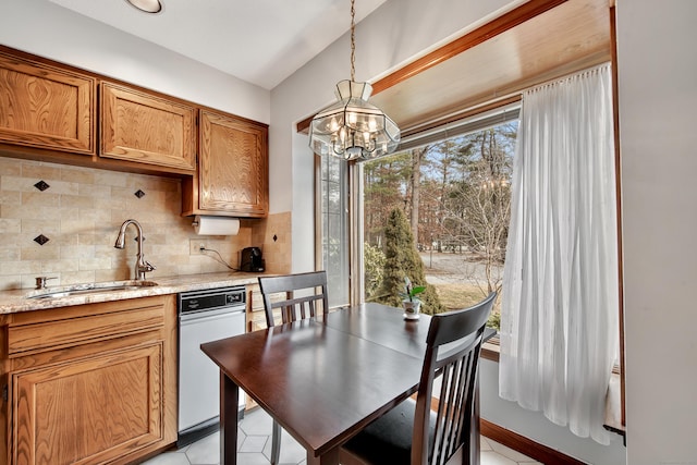 kitchen with tasteful backsplash, decorative light fixtures, brown cabinets, an inviting chandelier, and a sink